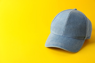 Photo of Stylish denim baseball cap on yellow background. Mockup for design