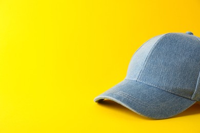 Photo of Stylish denim baseball cap on yellow background. Mockup for design