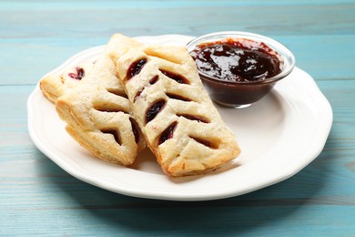 Photo of Delicious puff pastries and jam on light blue wooden table, closeup