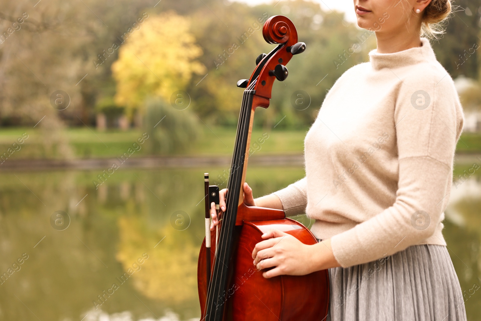 Photo of Young woman with cello in park, closeup. Space for text