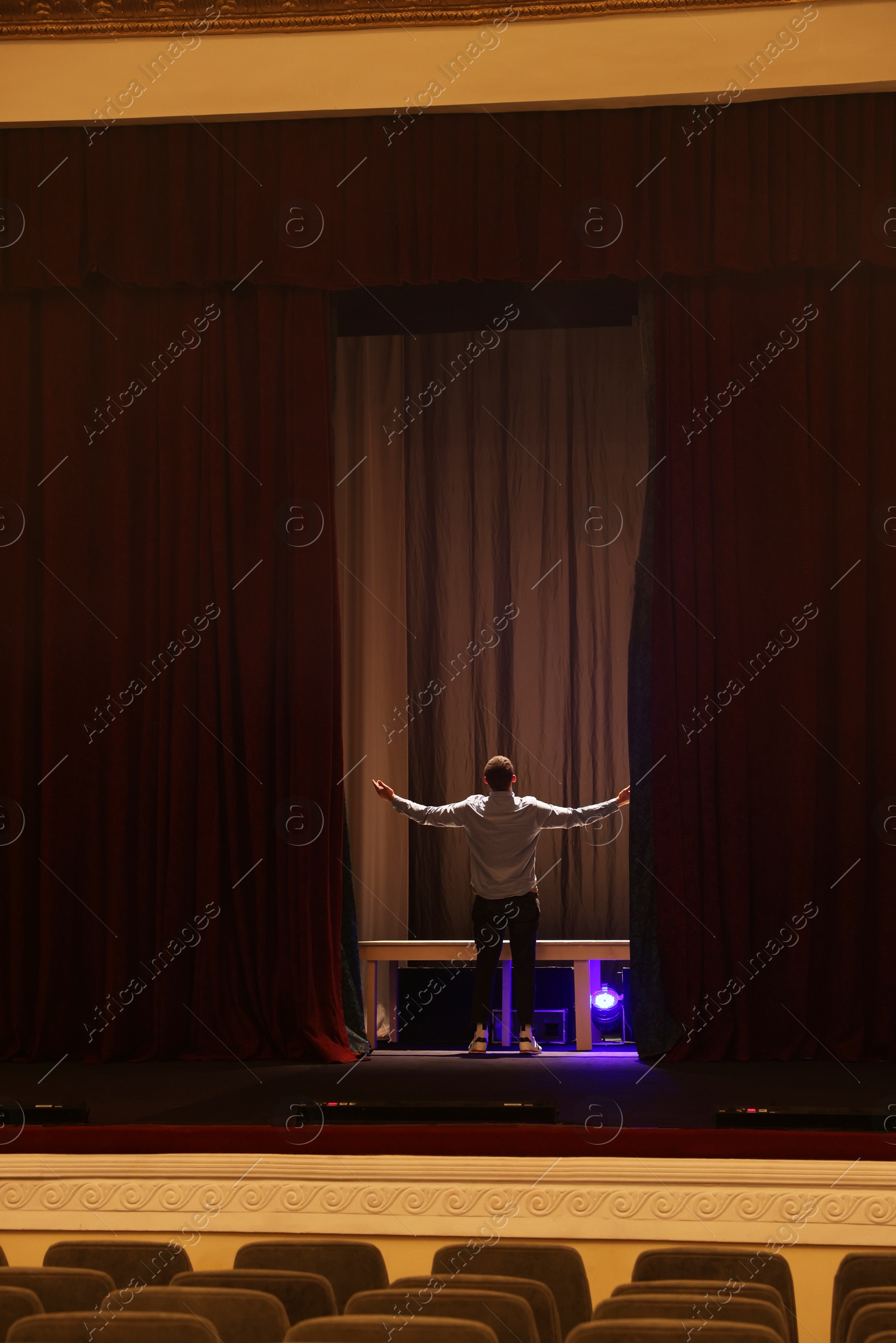 Photo of Professional actor rehearsing on stage in theatre, back view