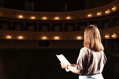 Professional actress rehearsing on stage in theatre, back view