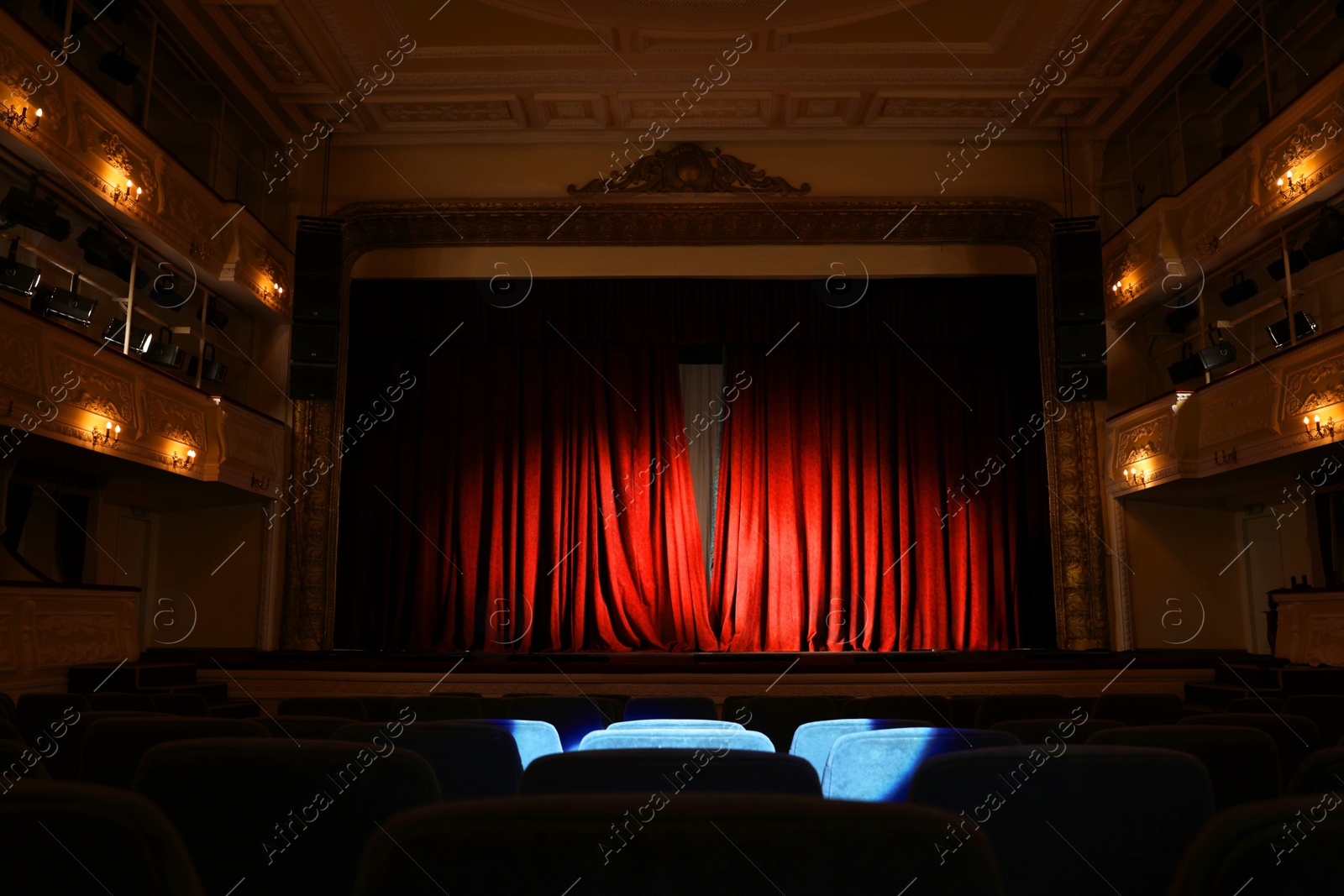 Photo of Elegant closed red curtains illuminated by spotlight in theatre