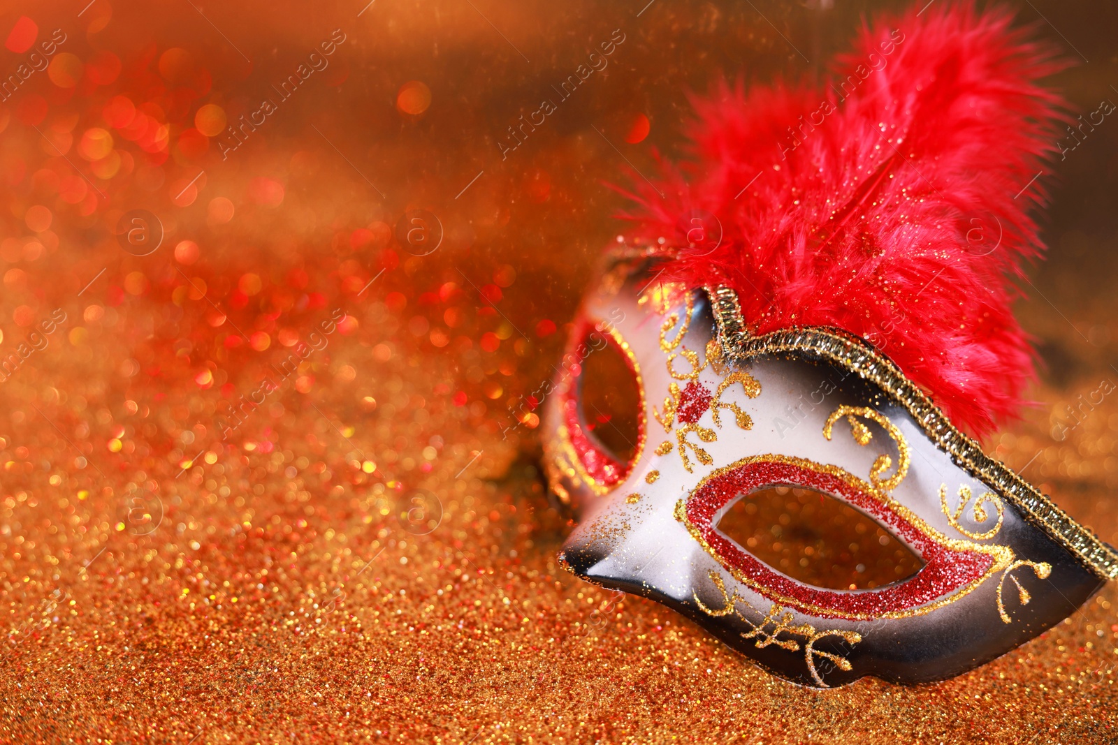 Photo of Beautiful carnival mask on shiny color background, closeup. Space for text