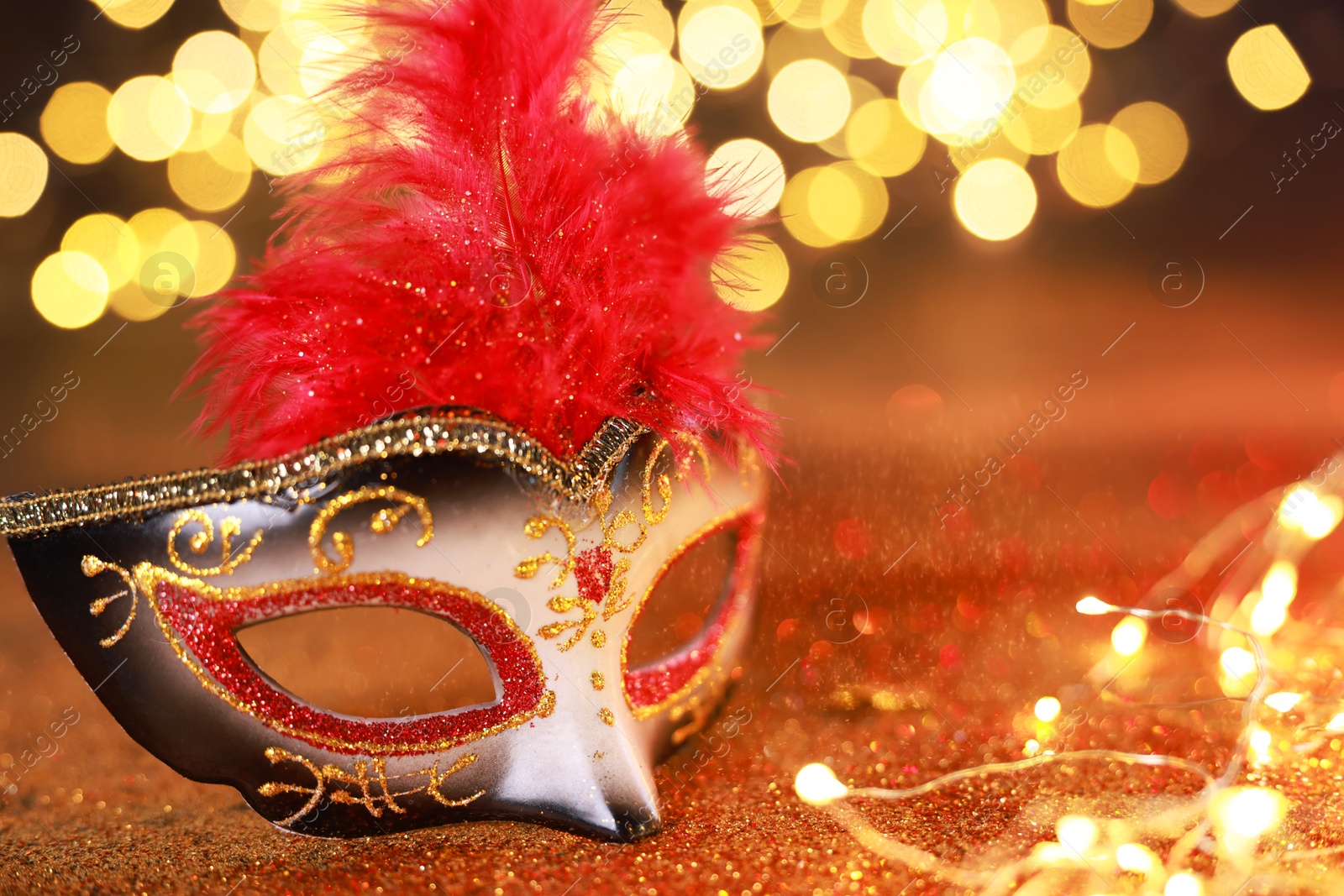 Photo of Beautiful carnival mask on shiny color background, closeup. Bokeh effect