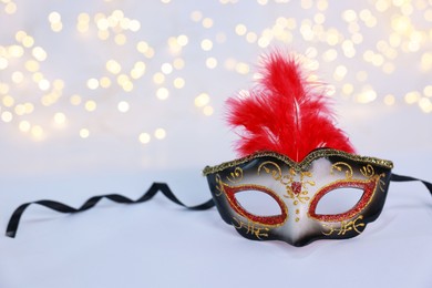 Photo of Beautiful carnival mask on color background, bokeh effect. Space for text