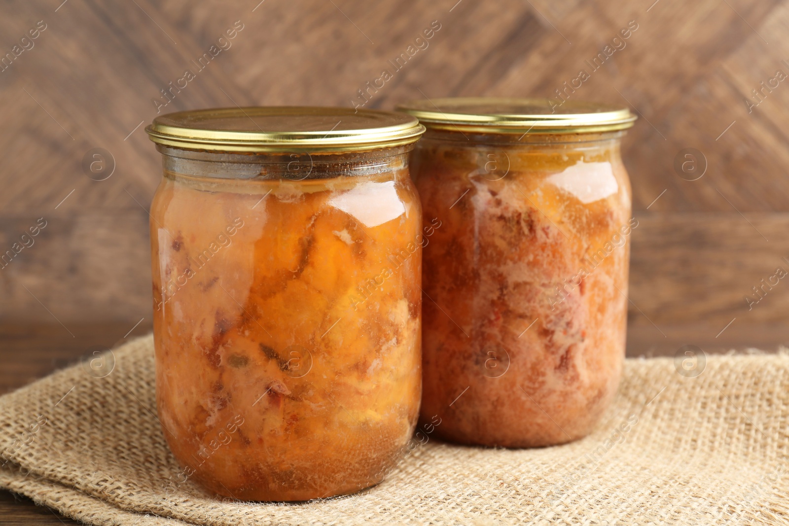 Photo of Canned meat in glass jars on table, closeup