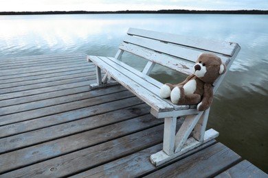 Photo of Lonely teddy bear on bench near river