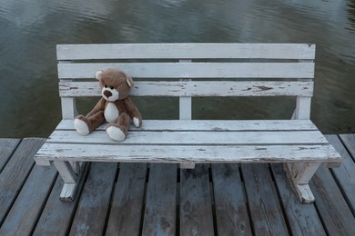 Photo of Lonely teddy bear on bench near river