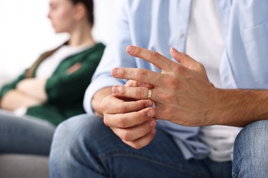 Photo of Man taking off engagement ring after quarrel with his wife at home, closeup