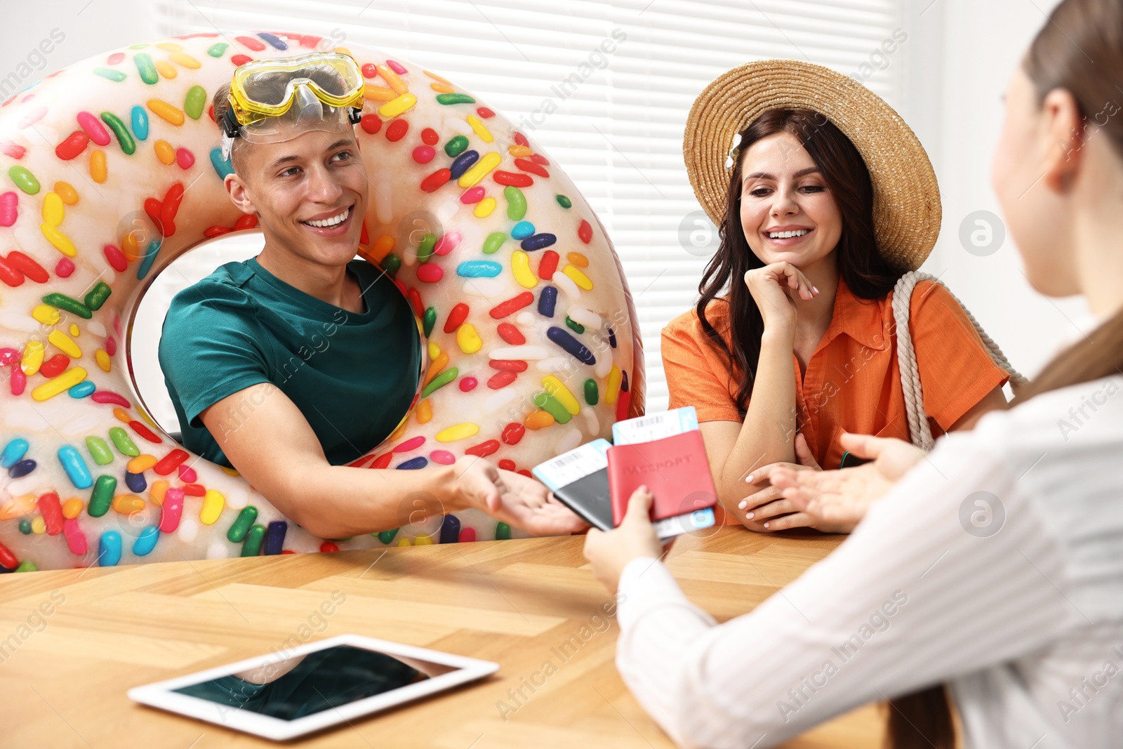 Photo of Happy couple planning vacation with travel agent at wooden table in office