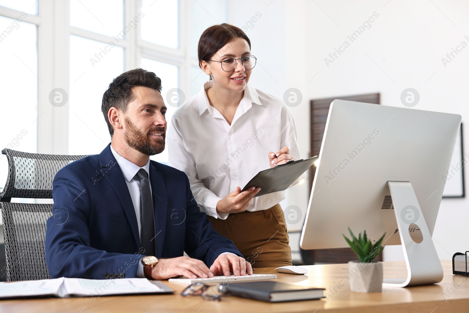 Photo of Colleagues working with computer at desk in office