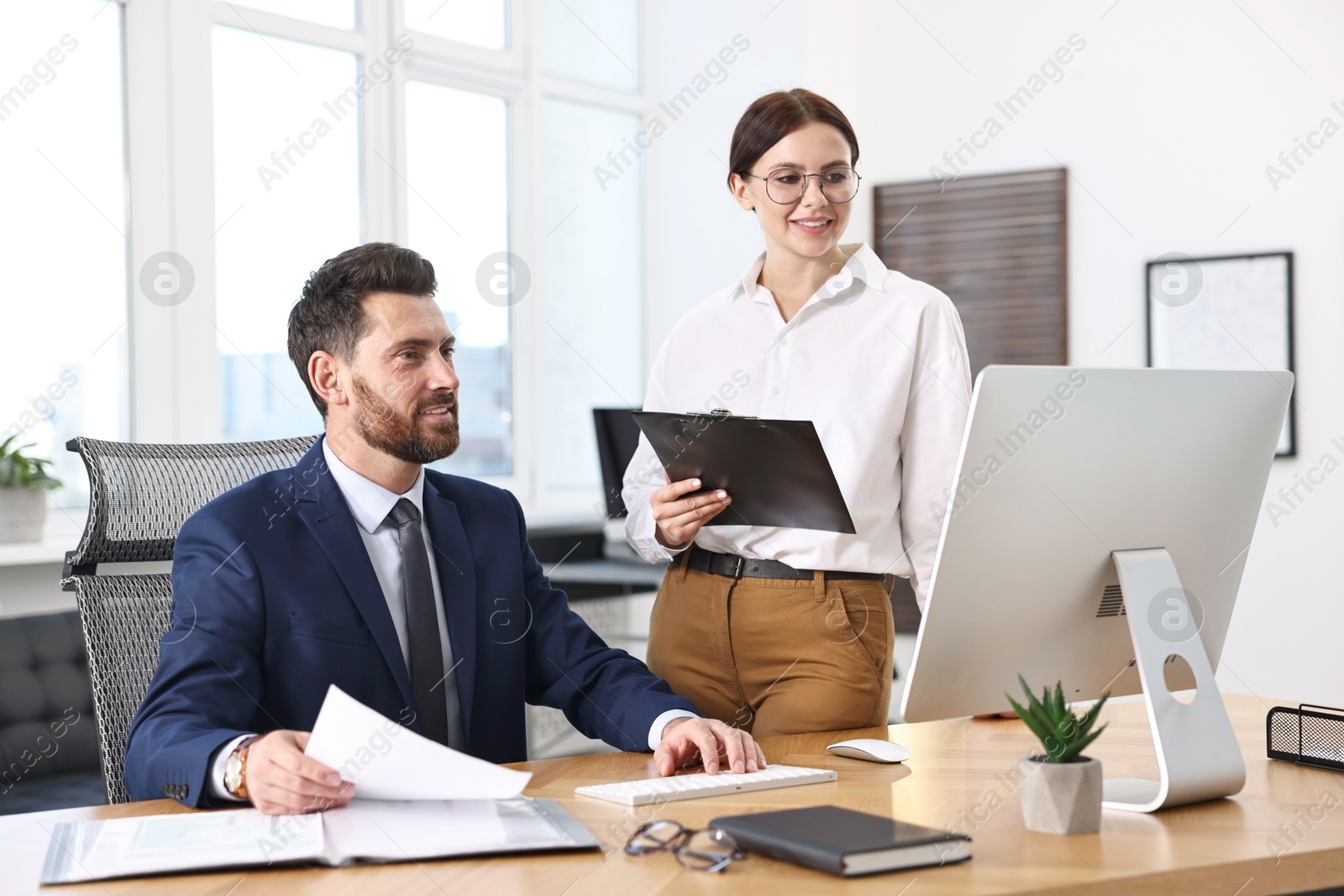 Photo of Colleagues working with computer at desk in office