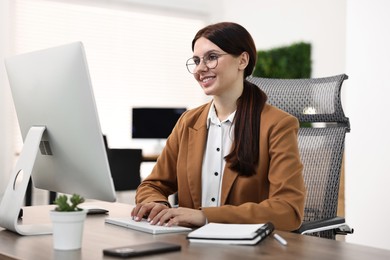 Photo of Woman working on computer at table in office