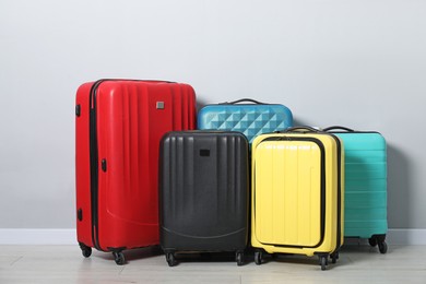 Photo of Many colorful suitcases on floor near light wall