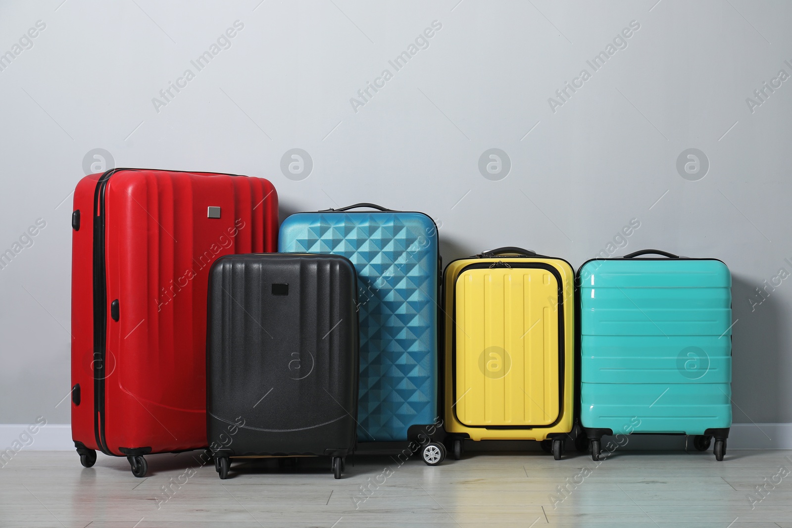 Photo of Many colorful suitcases on floor near light wall