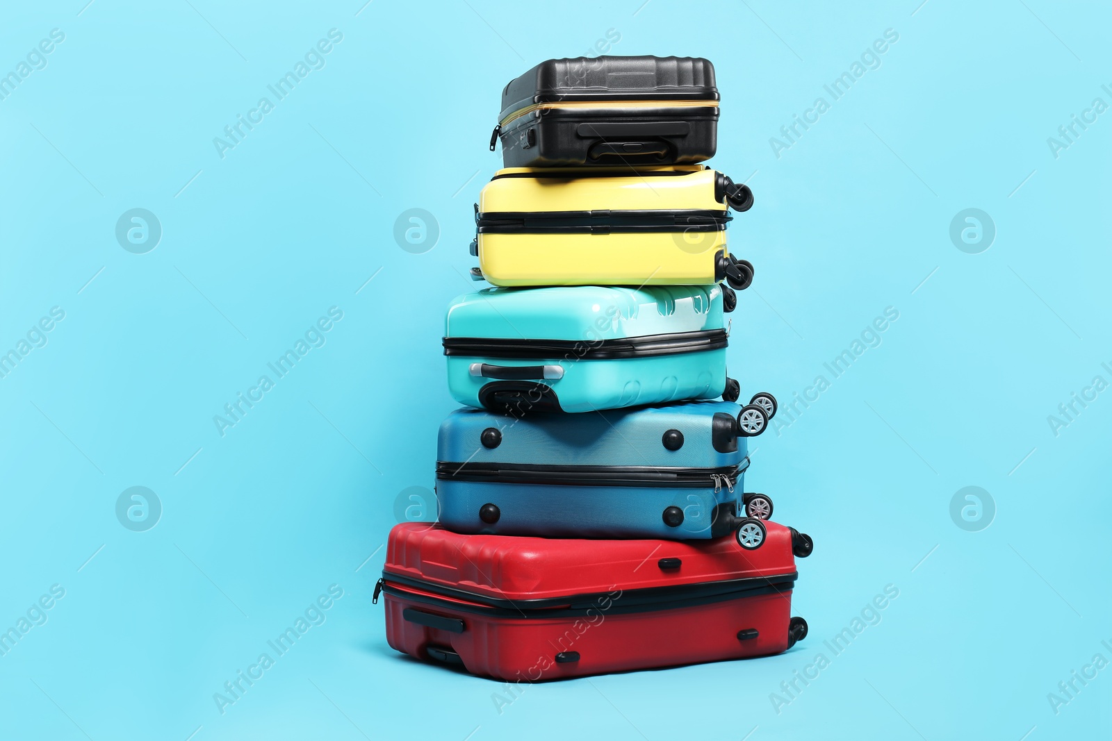 Photo of Stack of colorful suitcases on light blue background