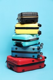 Photo of Stack of colorful suitcases on light blue background