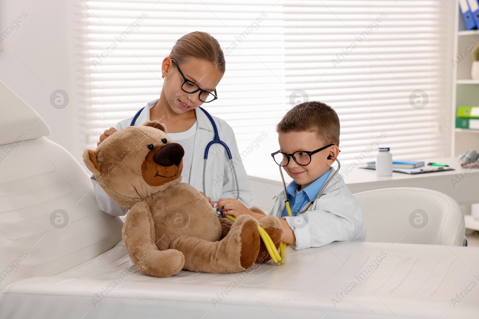 Photo of Little boy and girl with toy pretending to be doctors indoors