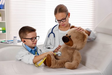 Photo of Little boy and girl with toy pretending to be doctors indoors