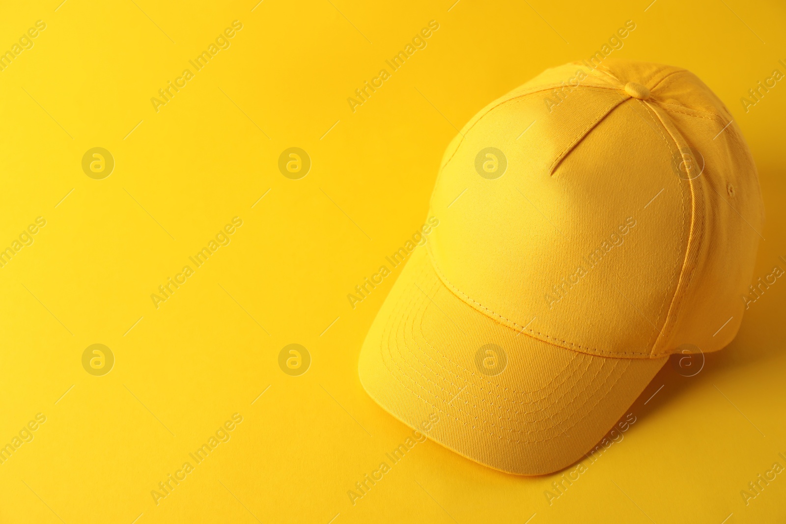 Photo of Stylish baseball cap on yellow background. Mockup for design