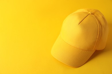 Photo of Stylish baseball cap on yellow background. Mockup for design