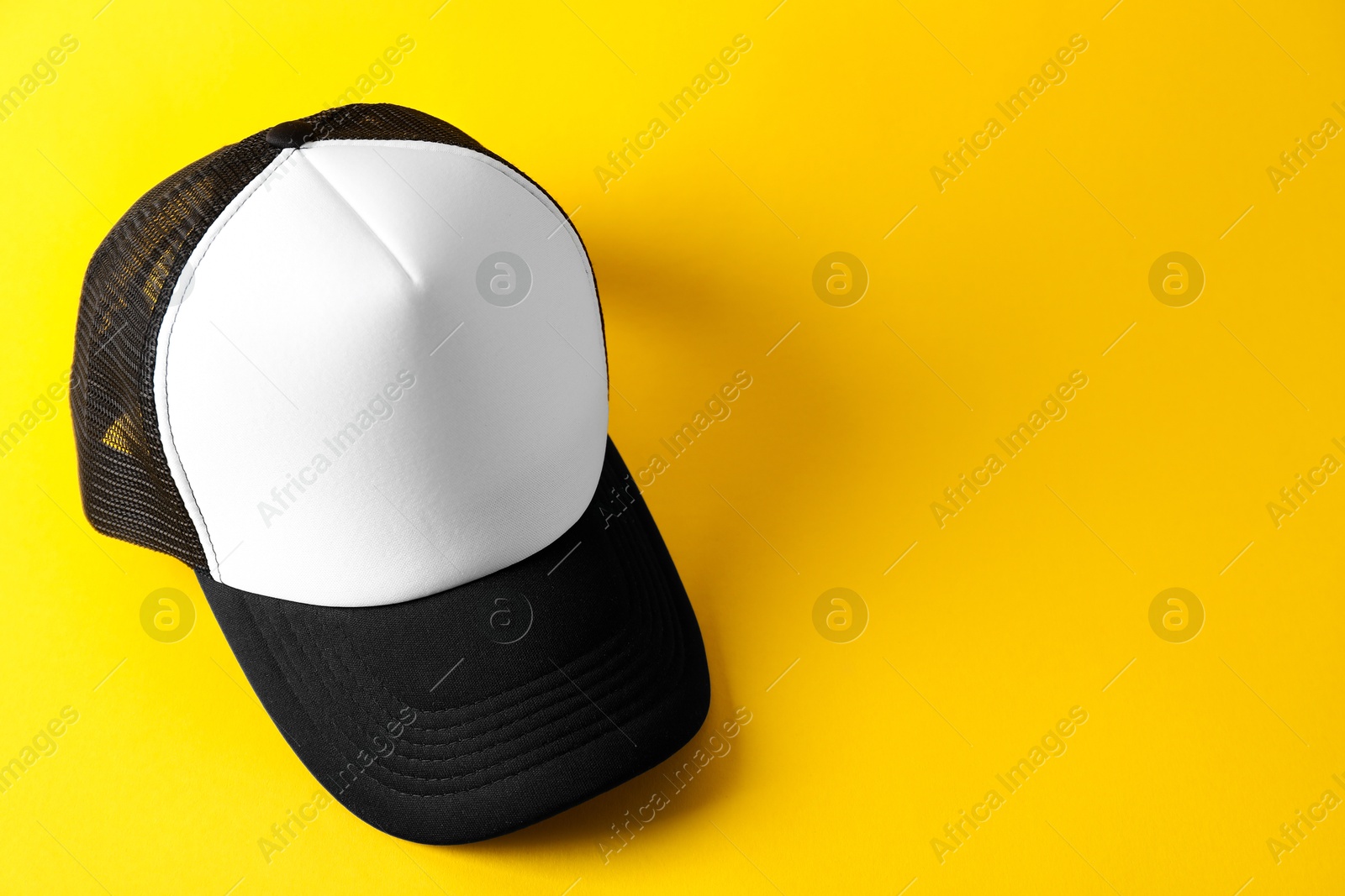 Photo of Stylish baseball cap on yellow background. Mockup for design