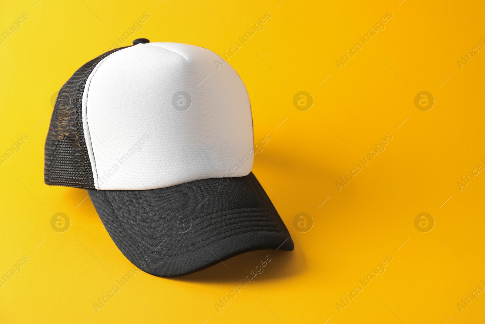 Photo of Stylish baseball cap on yellow background. Mockup for design