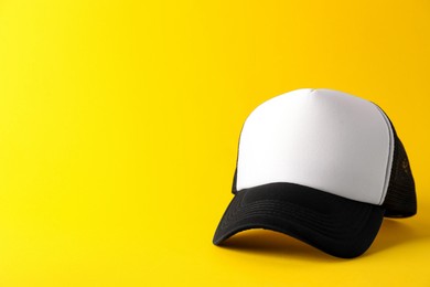 Photo of Stylish baseball cap on yellow background. Mockup for design