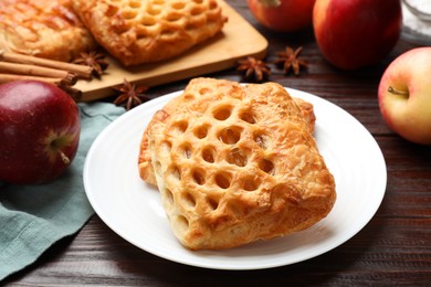 Photo of Delicious puff pastries, apples, cinnamon and anise stars on wooden table, closeup