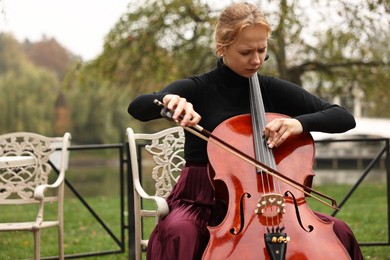 Photo of Beautiful young woman playing cello in park