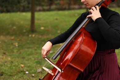 Photo of Young woman playing cello outdoors, closeup. Space for text