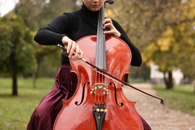 Photo of Young woman playing cello in park, closeup