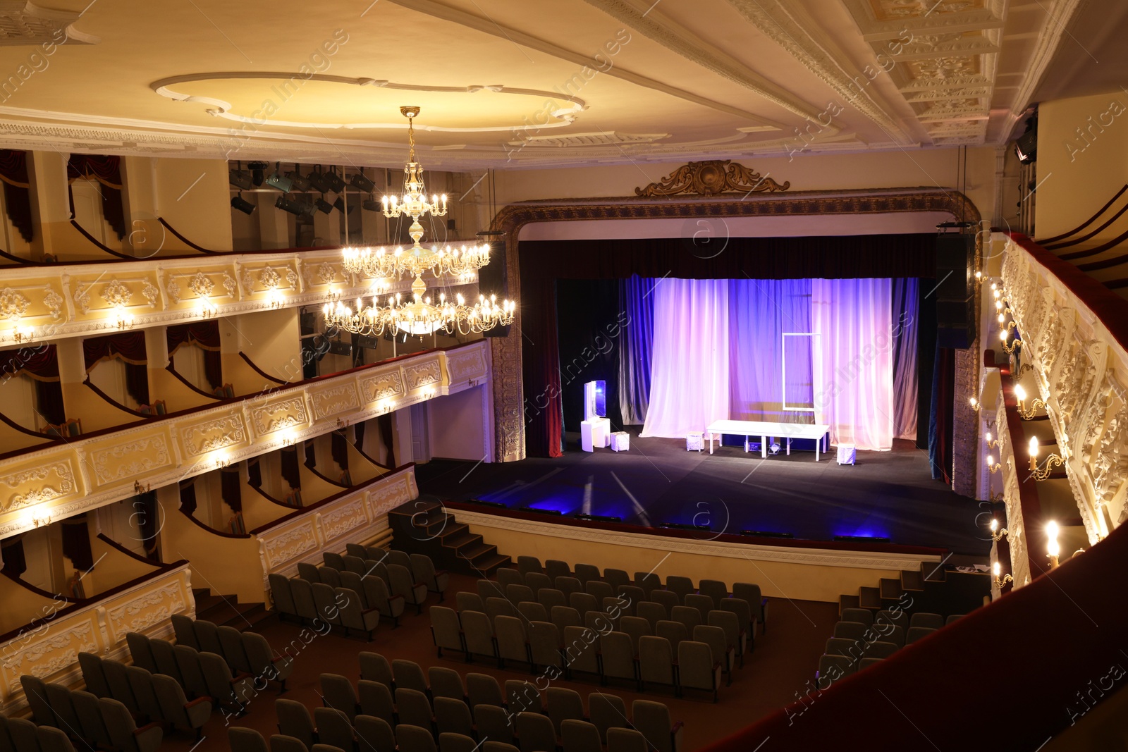 Photo of Theatre interior with stage, rows of comfortable seats and beautiful chandelier