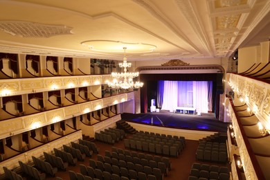 Photo of Theatre interior with stage, rows of comfortable seats and beautiful chandelier