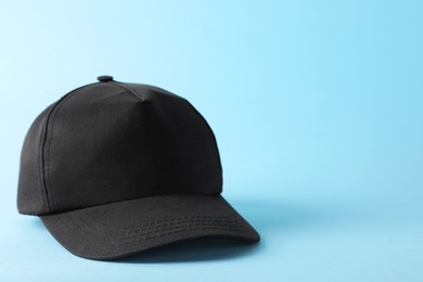 Photo of Stylish black baseball cap on light blue background. Mockup for design