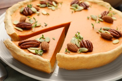 Photo of Tasty homemade pumpkin pie with nuts and seeds on table, closeup