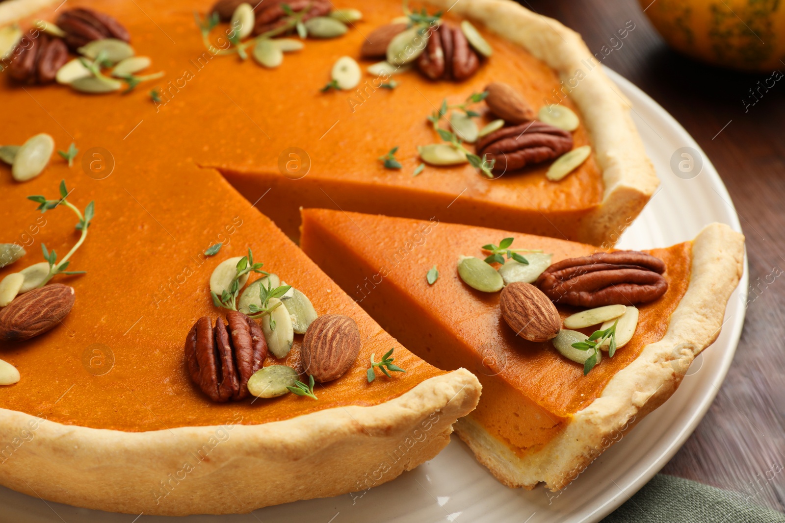 Photo of Tasty homemade pumpkin pie with nuts and seeds on table, closeup