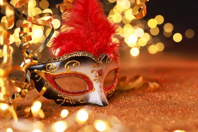 Photo of Beautiful carnival mask on shiny color background, bokeh effect. Space for text