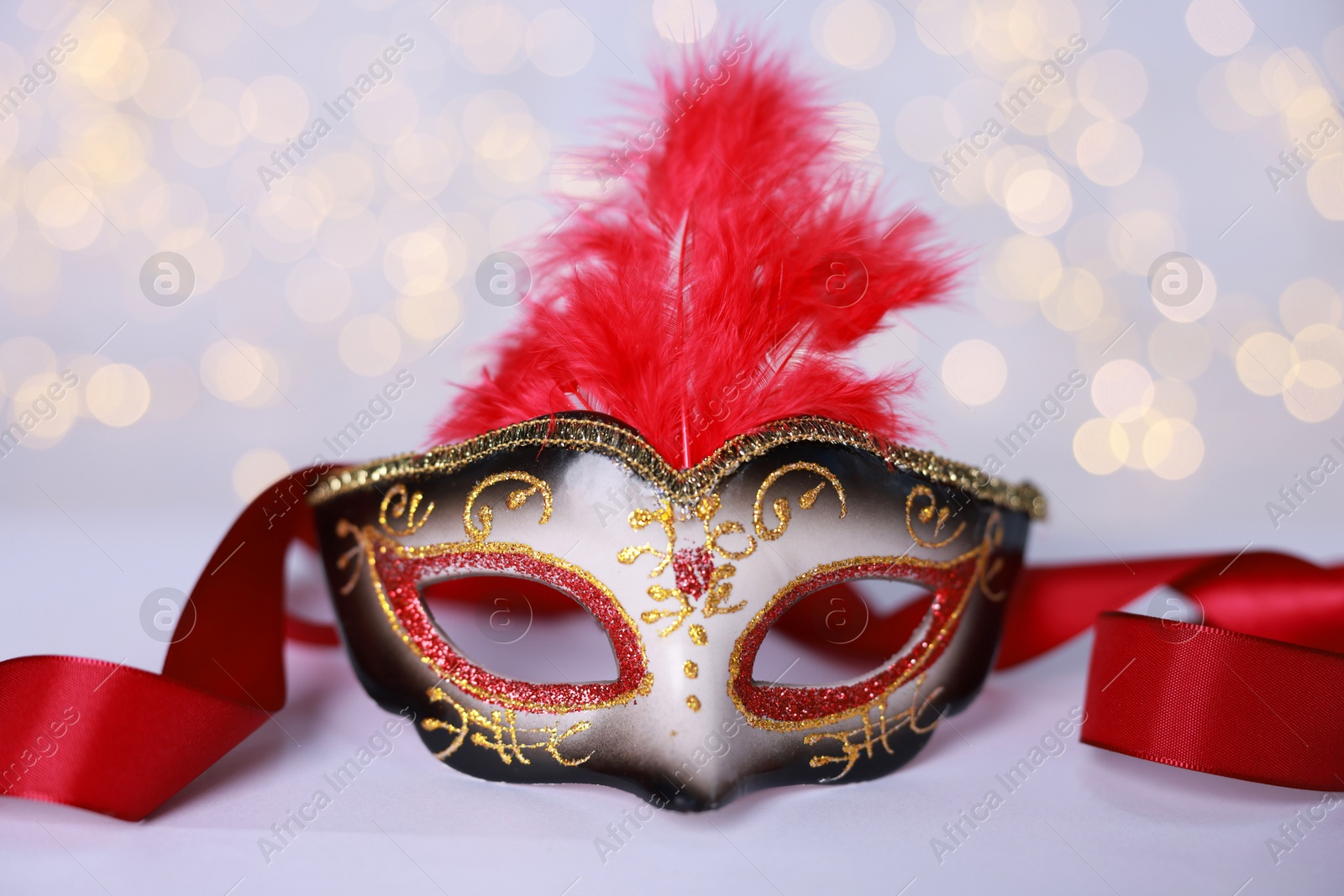 Photo of Beautiful carnival mask on color background, closeup. Bokeh effect