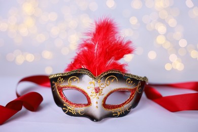 Photo of Beautiful carnival mask on color background, closeup. Bokeh effect