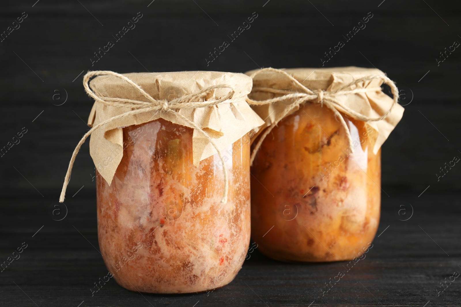 Photo of Canned meat in glass jars on wooden table, closeup