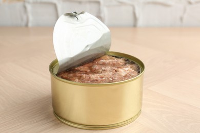 Canned meat in tin can on wooden table, closeup