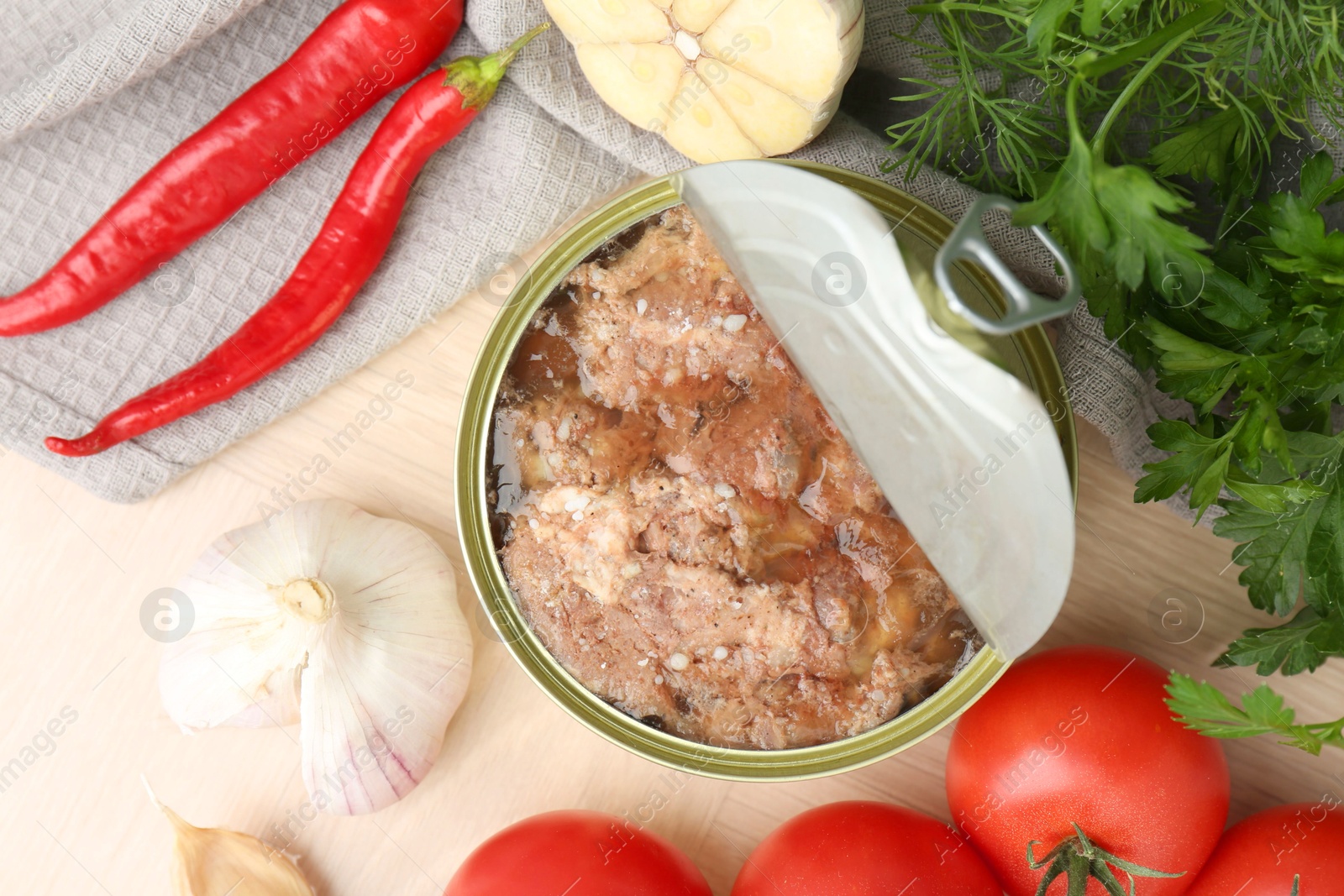 Photo of Canned meat in tin can and other products on wooden table, top view