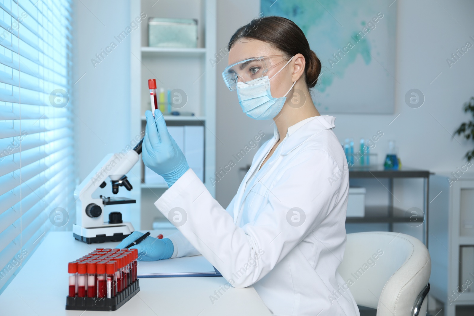 Photo of Laboratory testing. Doctor holding test tube with blood sample at table indoors