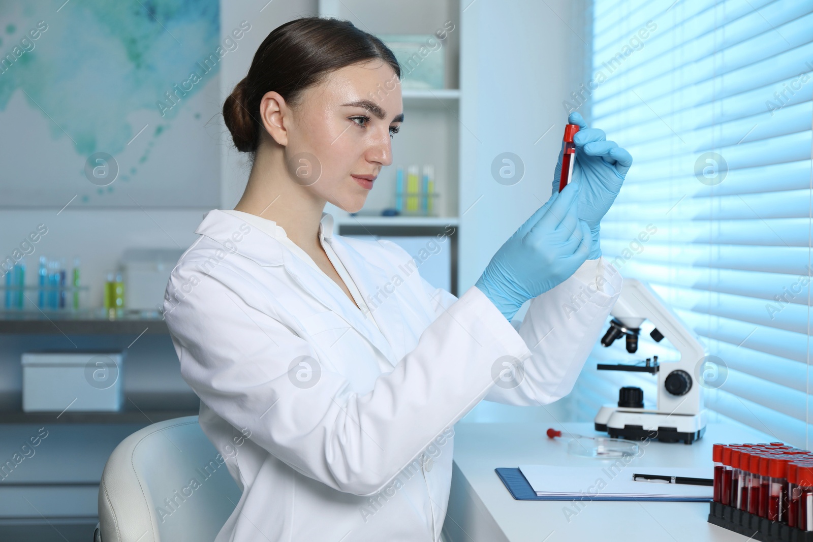 Photo of Laboratory testing. Doctor holding test tube with blood sample at table indoors