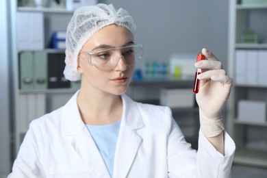 Laboratory testing. Doctor holding test tube with blood sample indoors