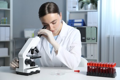 Laboratory testing. Doctor working with microscope at table indoors