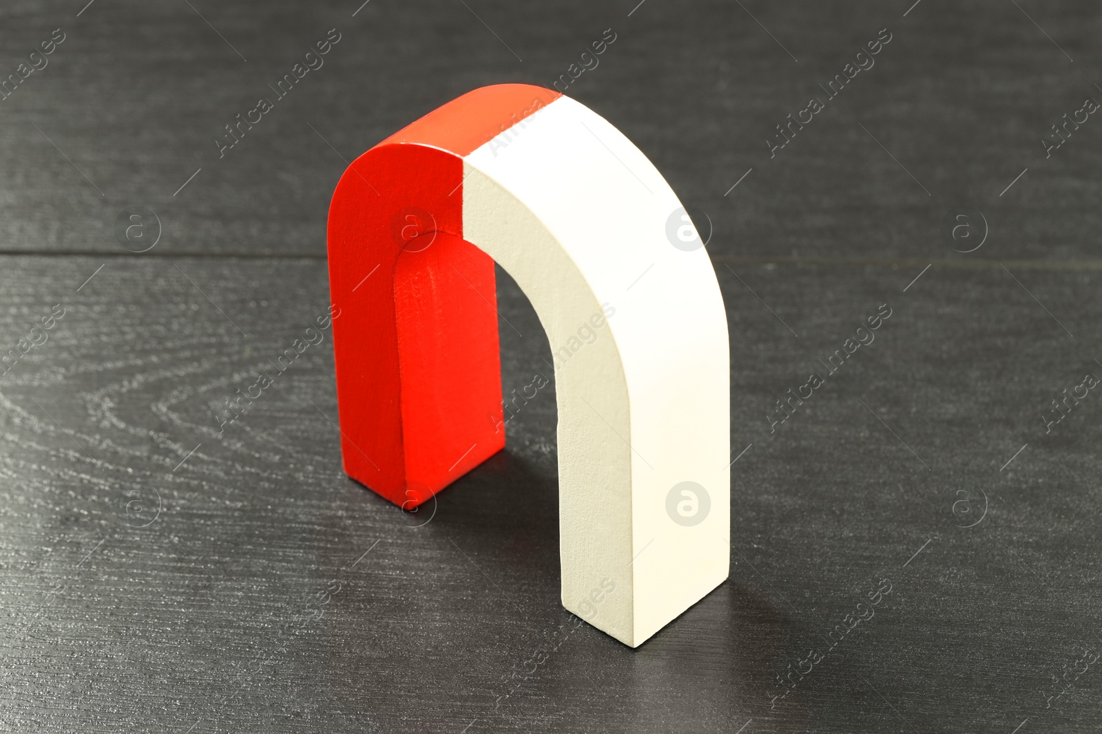 Photo of One horseshoe magnet on black wooden table, closeup