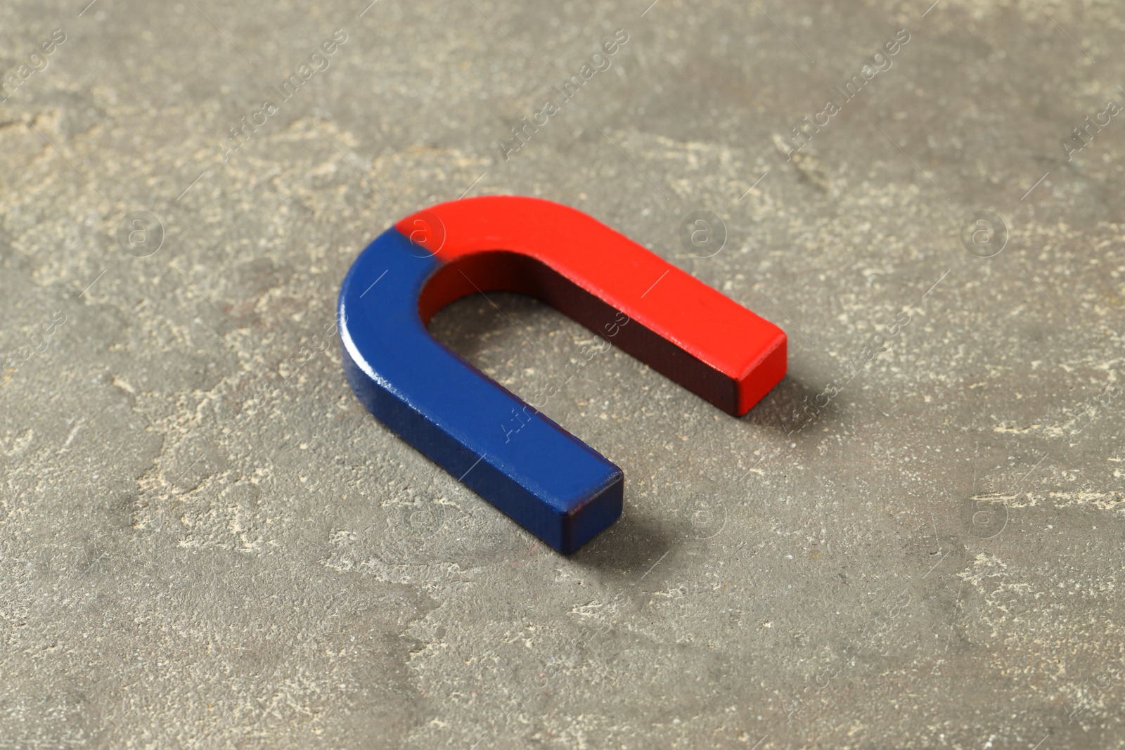 Photo of One horseshoe magnet on grey textured table, closeup